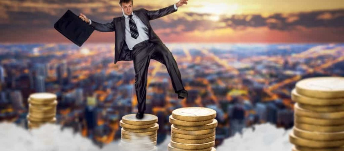 Businessman jumping on stacks of coins. Fragile unstable business, bankruptcy risk, financial balance